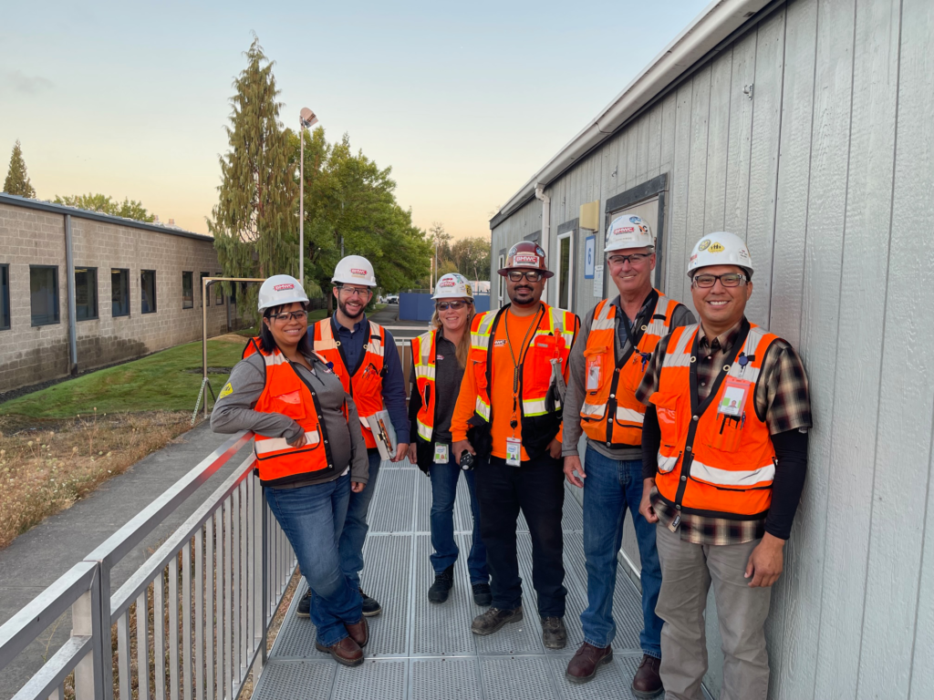 group of bmwc construction workers with hard have representing diversity, equity, and inclusion wearing hard hats and orange hiviz vests on jobsite 