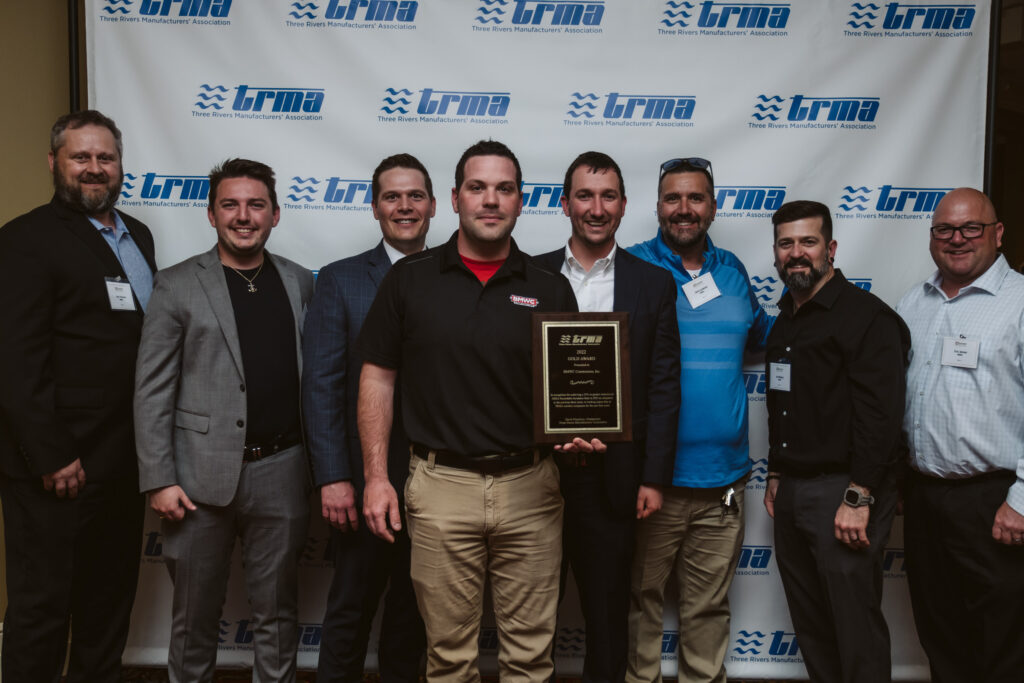 Men standing in front of TRMA backdrop holding Three Rivers Manufacturing Association’s (TRMA) Gold Award plaque.